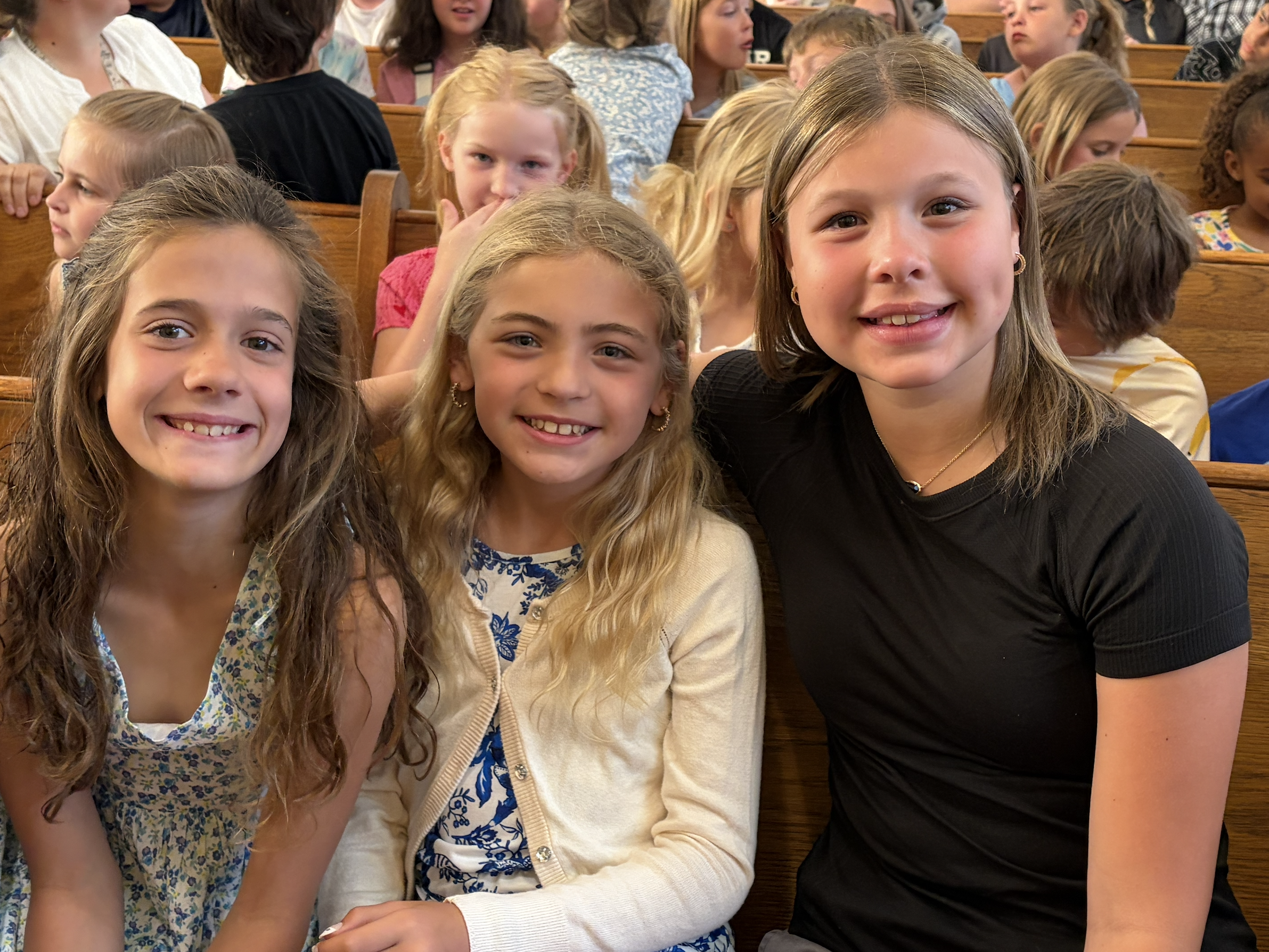 Three girls sitting together in chapel at St. Paul's Lutheran School as part of the Buddy Program